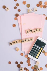 Mise à plat des essentiels des petites entreprises avec calculatrice, calendrier, pièces de monnaie et tuiles.