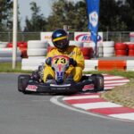 Un coureur en kart jaune number 73 tourne un virage sur circuit